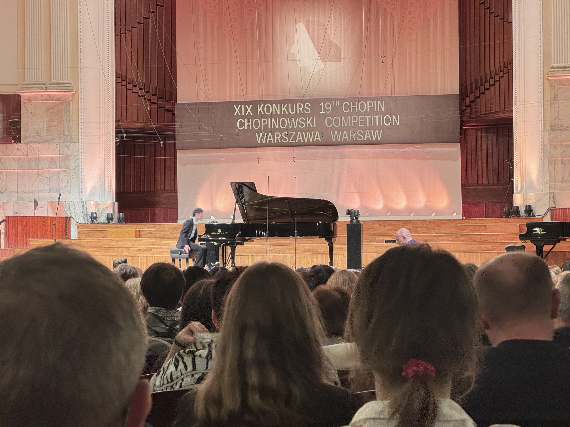 ショパン国際ピアノコンクール会場 ──ステージで演奏するコンテスタントと『XIX KONKURS CHOPINOWSKI』のサイン