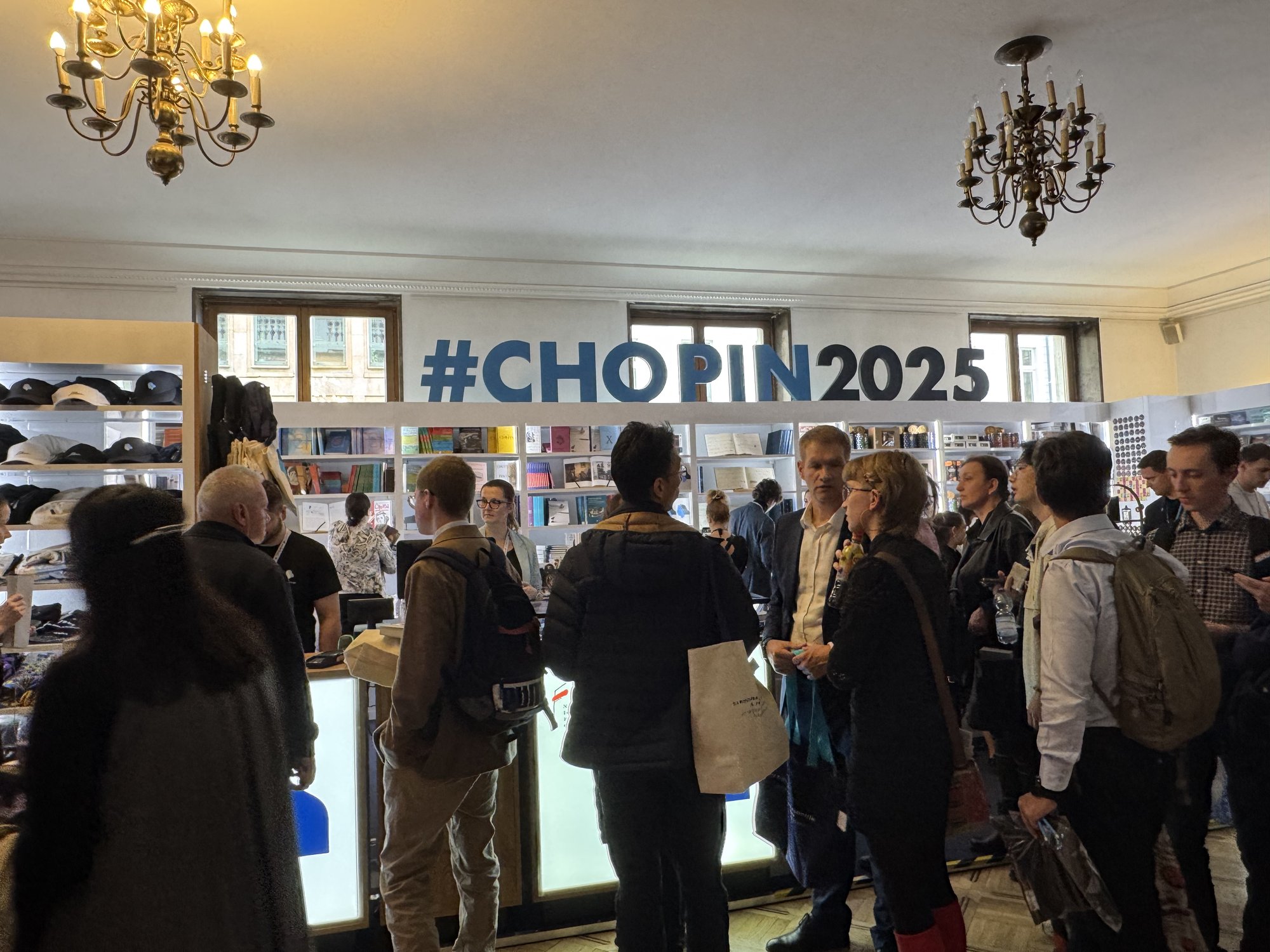 ショパン国際ピアノコンクール 会場内のグッズ売り場『#CHOPIN2025』──シャンデリアの下、賑わう人々